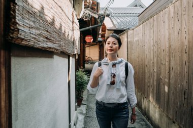 Kız backpacker ishibe sokak kyoto Japonya tipik dar sokaklarında yürüyüş. Genç Asyalı kadın güneş gözlüğü ile bambu perde ahşap evin üzerinde asılı az yolundaki rahatlatıcı neşeli.