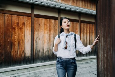 Genç kız backpacker ahşap duvar merakla iç içedir Festivali ile eski şehir gezi dokunmadan eller. kendini ishibe sokak kyoto Japonya sokakta duran kadın turist rehberi gezi.