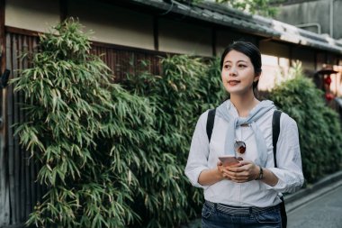 Kadın Asya turizm seyahat Bloglar bilgileri kullanarak cep telefonu pass bambu Bahçe Japon ahşap ev kyoto Japonya üzerinde göz. Kız yolu ile kullanma smartphone yürüyüşte açık havada gezinme