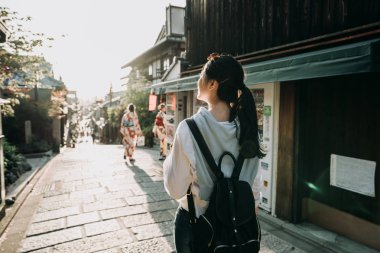 arkadan görünüşü Genç Asyalı kadın backpacker yürüyüş zevk günbatımı Japon geleneksel sokak köşesinde satıcı makinesiyle. iki renkli elbise Hanamikoji Dori kyoto kimono içinde yerel kız