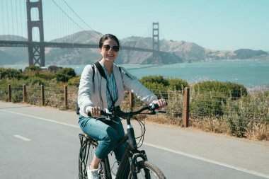 Asyalı kadın rahatlatıcı ve güneş binicilik bisiklet gezisi San Francisco Kaliforniya ABD kırsal zevk. Genç kız seyahat gezi golden gate köprüsü yaz aylarında kıyı şeridi boyunca.