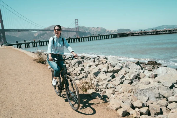 golden gate köprüsü san francisco Kaliforniya ABD gezi gülümseyen kadın binicilik bisiklet seyahat. Genç Bayan güneş gözlüğü plaj deniz okyanus boyunca Bisiklete binme neşeli. Bisiklet üzerinde kadın backpacker.