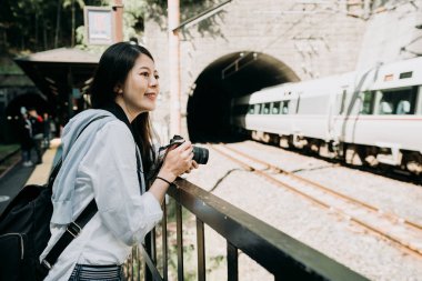 Kyoto Japonya'da emin gülümseme alma resim hızlı tren ile profesyonel slr kamera tutan Genç Asyalı kadın fotoğrafçı. Kız backpacker demiryolu mağara açık duran neşeli.