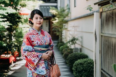 Yerel Japon kadın ayakta açık evinin önünde ağaçlar ve bitkiler bambu kapı yakınındaki ile Bahçe gülümseyerek. çiçek renkli kimono elbise altında güneş ışığı bekleyen genç kız.