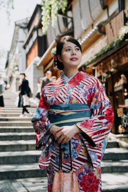 Merdivenlerde sannen zaka uzun renkli kimono elbise sokak üzerinde duran yerel Japon kadın. geleneksel bez meraklı gezi satıcı mağaza dükkan arka planda gülümseyen genç kız.