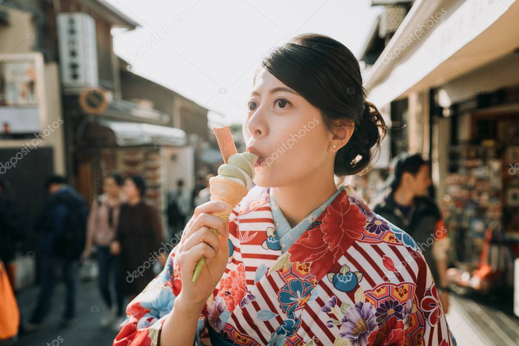 japanese young teenage girl in flower kimono dress join having fun in summer festival join temple fair. happy woman in traditional cloth eating matcha ice cream kyoto japan in hot teeming street