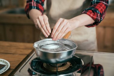 Eller su ocakta kakao pişirme ile Pota kase ortasına çikolata parçaları koyarak odaklanmak. kadın sevgilisi koca mutfak yalnız için Sevgililer günü el yapımı hediyelik tatlı hazırlamak.