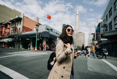 kadın backpacker chinatown açık havada sokakta yürümek. kırmızı Çin bayrağı mavi gökyüzü altında rüzgarda uçan binasında. San francisco Amerika'nın arka planda Transamerica Pyramid uzun kule.
