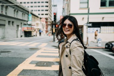 zebra baş yüz kamera gülümseyen dönüm çapraz üzerinde yürüyen güzel neşeli Bayan backpacker. Genç kız meşgul sokak san francisco ABD de yol yaz aylarında duran güneş gözlüklü. zarif Asyalı kadın