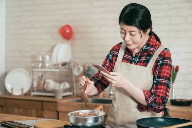 Sevimli Asya kadın yemek çikolata ocakta tencerede erime süreci ve Fotoğraf kompozisyon yazmak video mobil gadget kullanarak. genç kız el yapımı kakao şekerli tatlı Sevgililer günü.