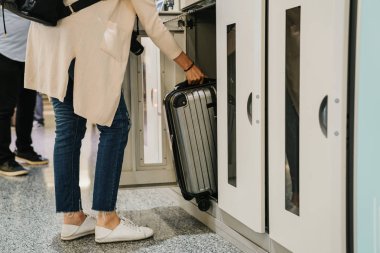 beyaz ayakkabı rahat kıyafet içinde tanınmayan Asyalı kadın bagaj emanet dolabına koyar. Asya turistler için bavul depozito saklama kutuları kullanın. Backpacker sikke konteyner havaalanında malzeme alır.
