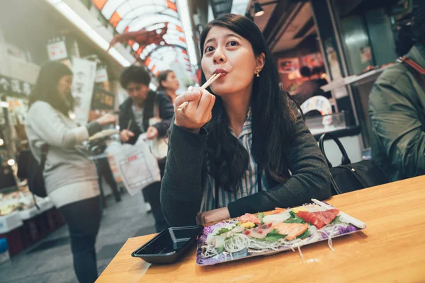 Mujer comer alimentos frescos y crudos atún sashimi — Foto de Stock