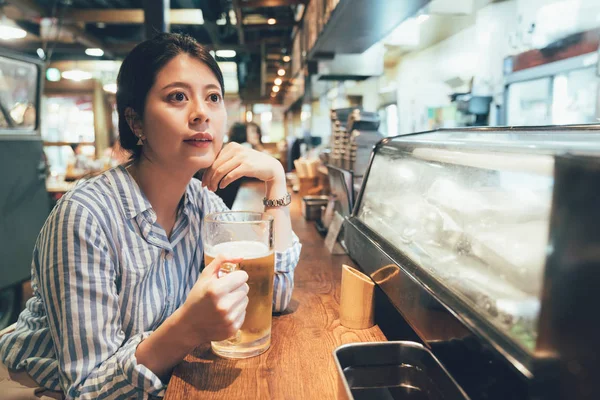 Woman holding beer sitting at bar counter — Stock Photo, Image