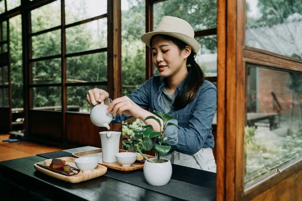 Femme avec chapeau mains versant théière — Photo