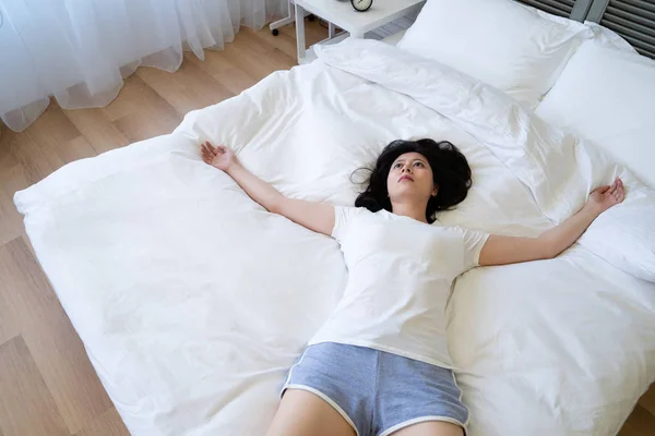 Woman lying on bed with arms outstretched — Stock Photo, Image