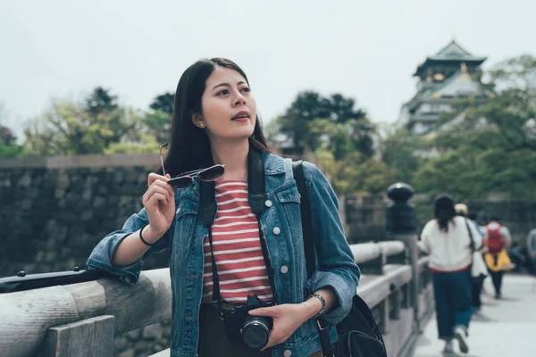 Woman looking aside holding camera — Stock Photo, Image