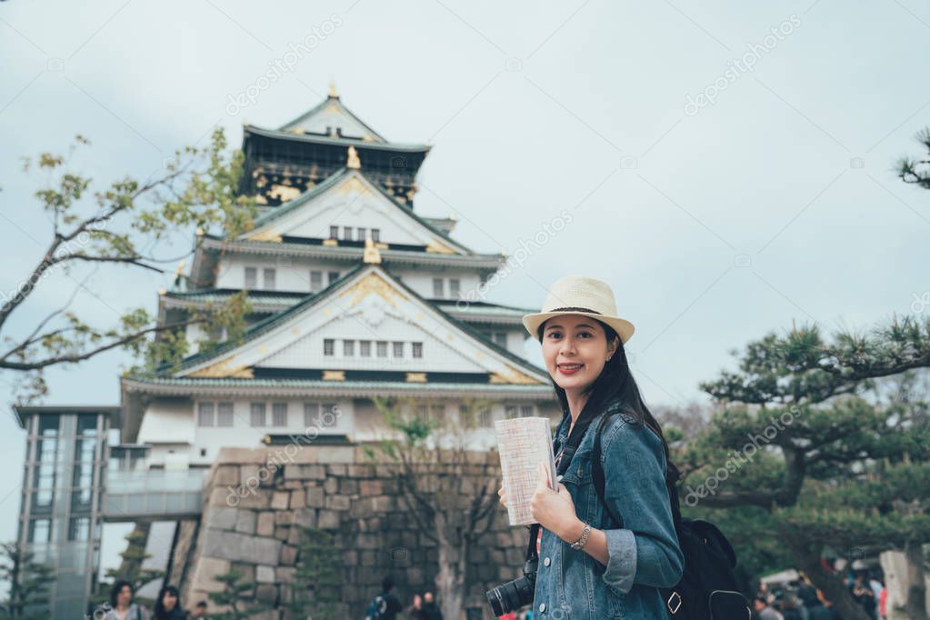 woman walking around osaka castle with guide book