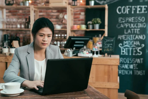 Kobieta pracuje na komputerze typu netbook w drewniany stół — Zdjęcie stockowe