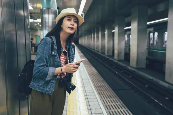 Traveler holding cellphone standing by railway — Stock Photo, Image