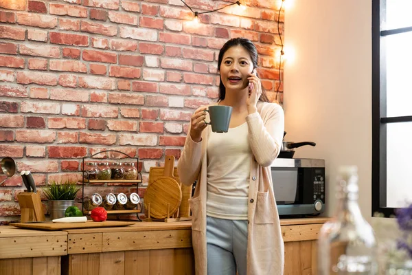 Asian woman with coffee and talking on cellphone — Stock Photo, Image