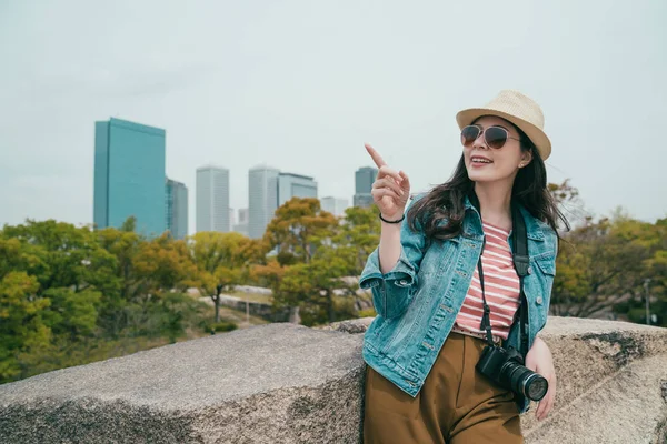Girl pointing to sky with background skyscraper — Stock Photo, Image