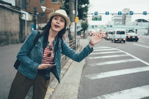 Asiatisk kvinde med hånd op ringer taxa - Stock-foto