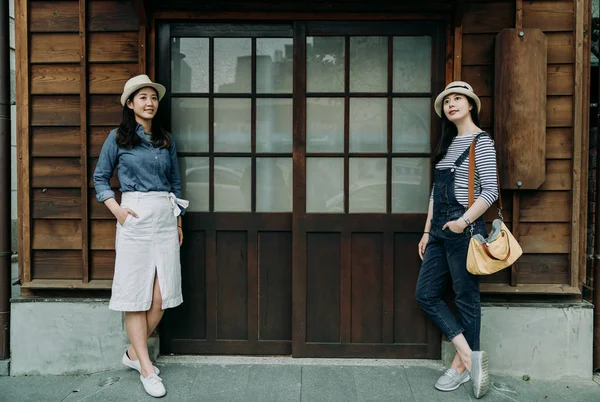 Mulheres turistas de pé contando com parede de madeira — Fotografia de Stock