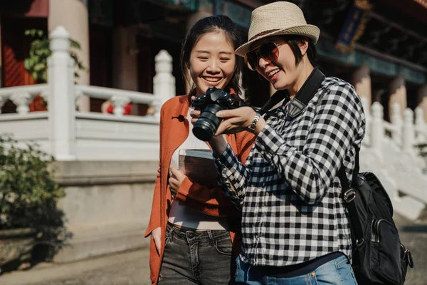 Fotógrafo feminino olhar na câmera mostrando amigo — Fotografia de Stock