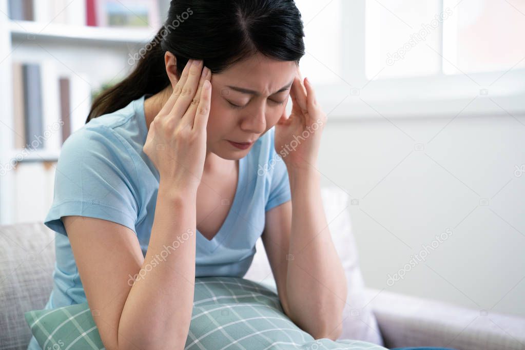 woman suffering from headache sitting on couch