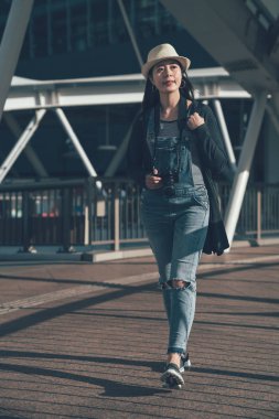 Asya kadın sırt çantası ile yaya köprüsü üzerinde yürüyüş