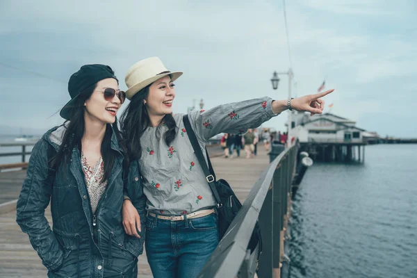 Meisjes lopen op houten brug boven de zee — Stockfoto