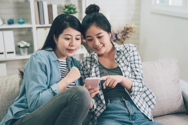 Meisjes delen koptelefoon wijzend Toon mobiele telefoon — Stockfoto
