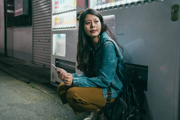 Female kneeling down rely on vending machine — Stock Photo, Image