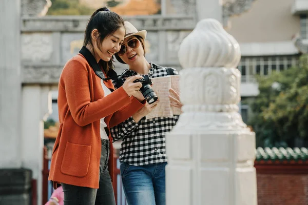 Mujeres de pie mirando de cerca comprobar la foto en la cámara — Foto de Stock