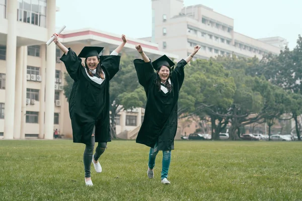 Mujeres graduadas sosteniendo diplomas sonriendo saltando —  Fotos de Stock