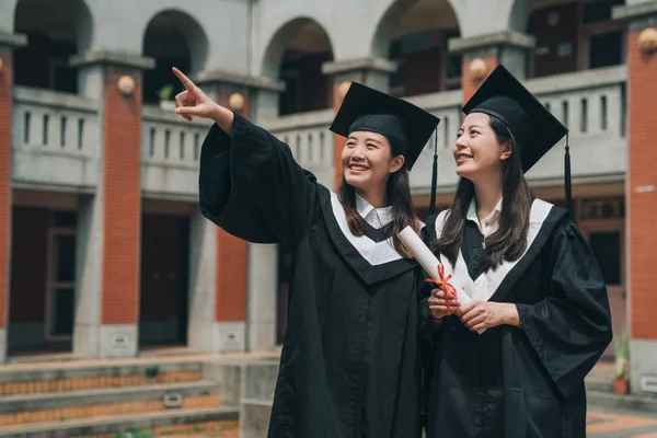 Estudiante universitario graduado sonriendo apuntando cielo —  Fotos de Stock