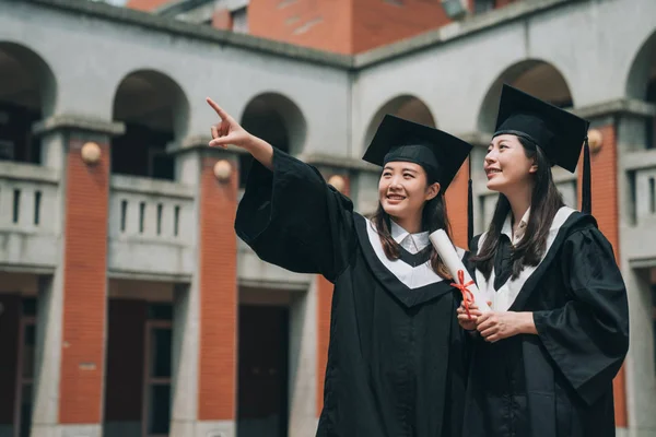 Chica universitaria en vestidos mostrando amigo dedo de punta —  Fotos de Stock