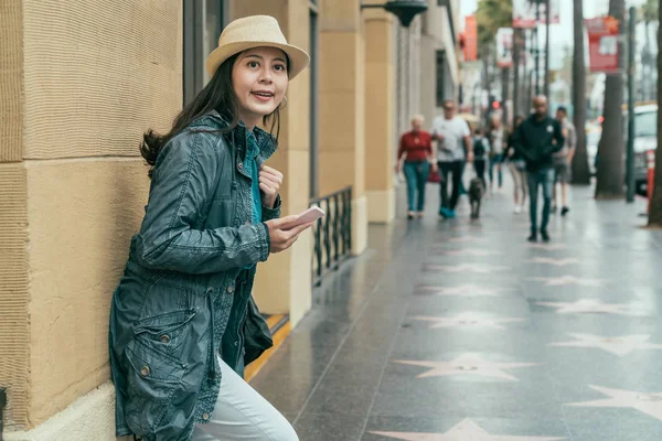 Menina em estilo urbano se inclina parede com smartphone — Fotografia de Stock
