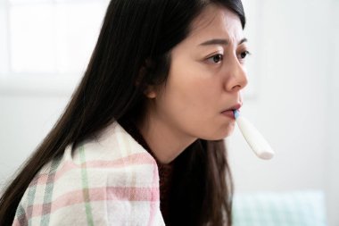 Kadın battaniyeyi ağzında termometreyle sarmış.