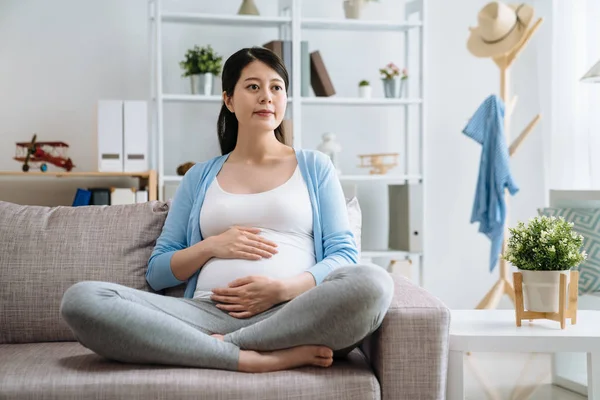 Kanepede oturan hamile mutlu gülümseyen kadın