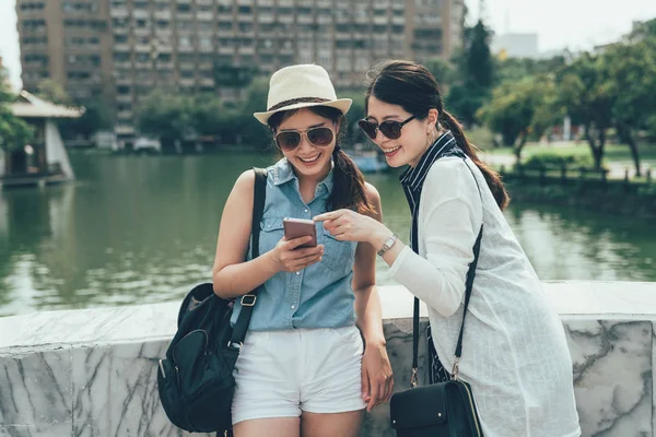 Vrienden leunend op stenen brug met behulp van mobiele telefoon — Stockfoto