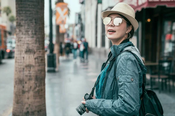 Girl backpacker holding camera standing on street — Stock Photo, Image