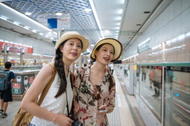 kapalı platformda tren bekleyen kız kardeşler.