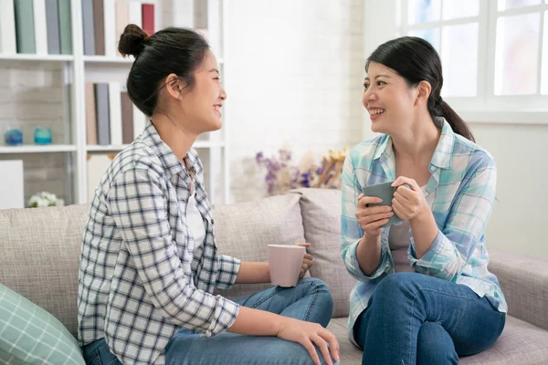 Gelukkig Aziatische zusters rusten op een bank in de woonkamer — Stockfoto