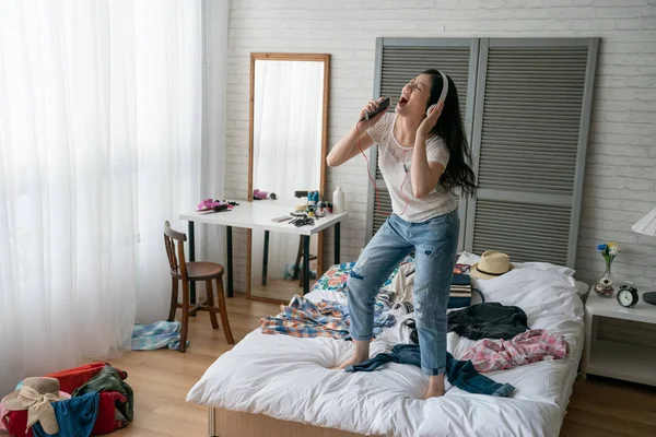 Wanita dengan earphone menari di tempat tidur putih yang nyaman — Stok Foto