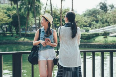 parkta gölet tarafından ahşap korkuluk yaslanmış gezginler