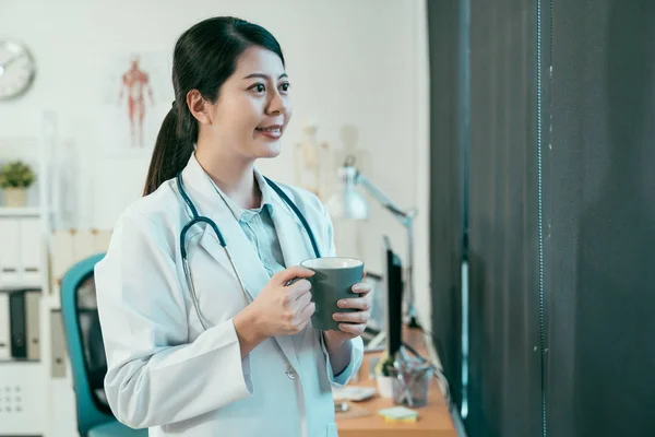 Medico femminile con tazza di caffè nello studio medico — Foto Stock