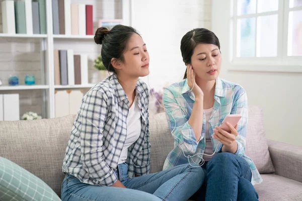 women relax in apartment sharing earphones