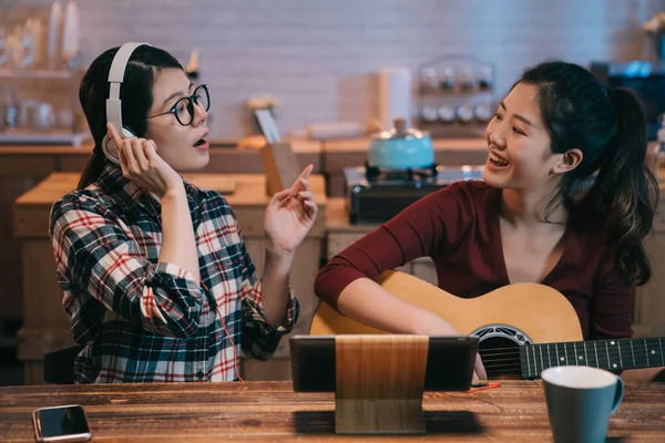 Mujer tocando guitarra acústica cantando con hermana — Foto de Stock