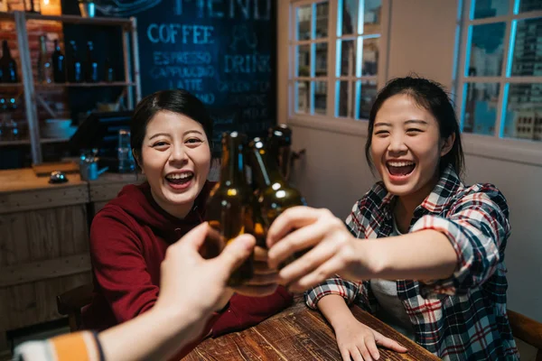 three female friends clinking bottles of beer